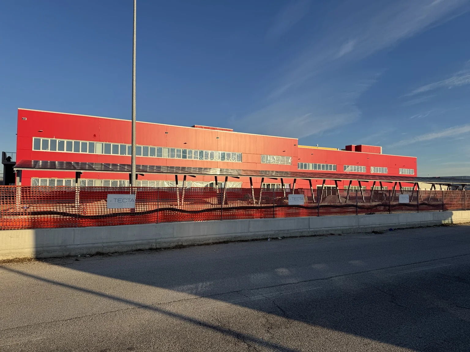 Prospetto rosso del complesso DHL Express con fascia continua di serramenti.